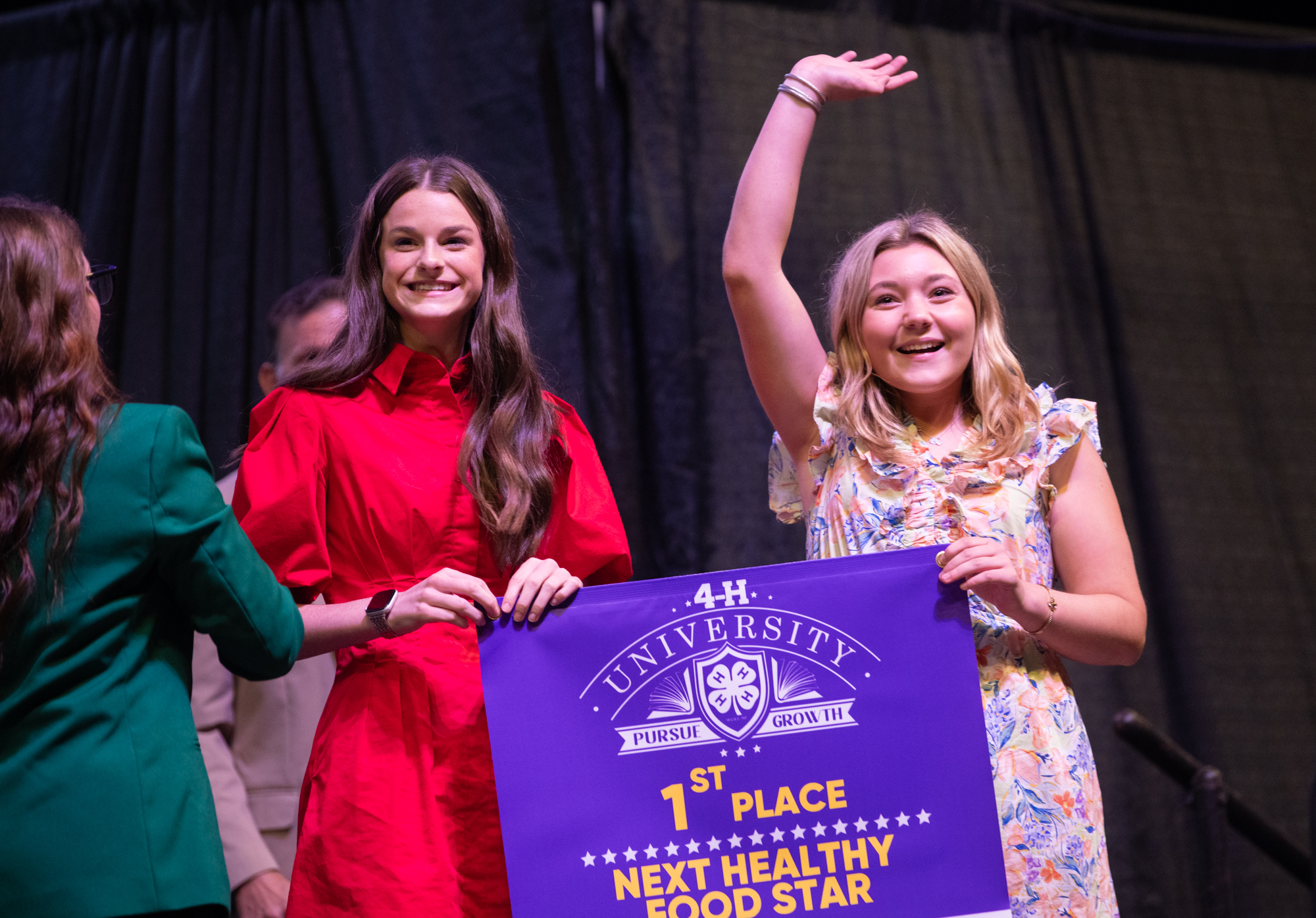Two people holding a ‘1st Place Next Healthy Food Star’ banner at a 4-H University event.